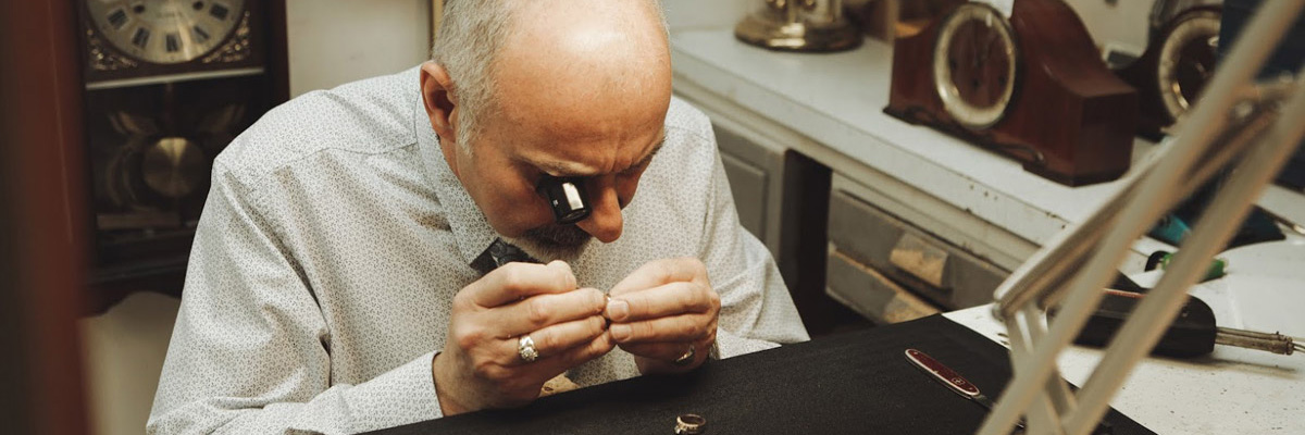 man closely examing ring with magnification microscope